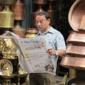 Zeitungsleser in Nepal, umgeben von Klangkörpern: Feuilletonisten schreiben für die Elite der Elite. Foto: Paul-Josef Raue